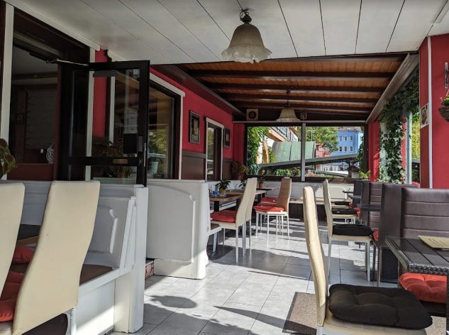 Überdachte Terrasse des Eiscafés Il Fiume mit Holzdecke und Pflanzen